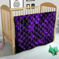 Purple and black Polynesian pattern quilt blanket on a wooden baby crib