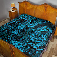 Blue Polynesian pattern quilt laid on bed, with dark border and tiki and flower motifs.
