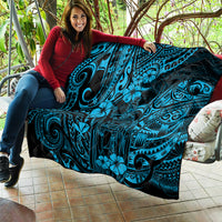 Blue Polynesian pattern quilt draped over a couch, with dark border and tiki motifs.
