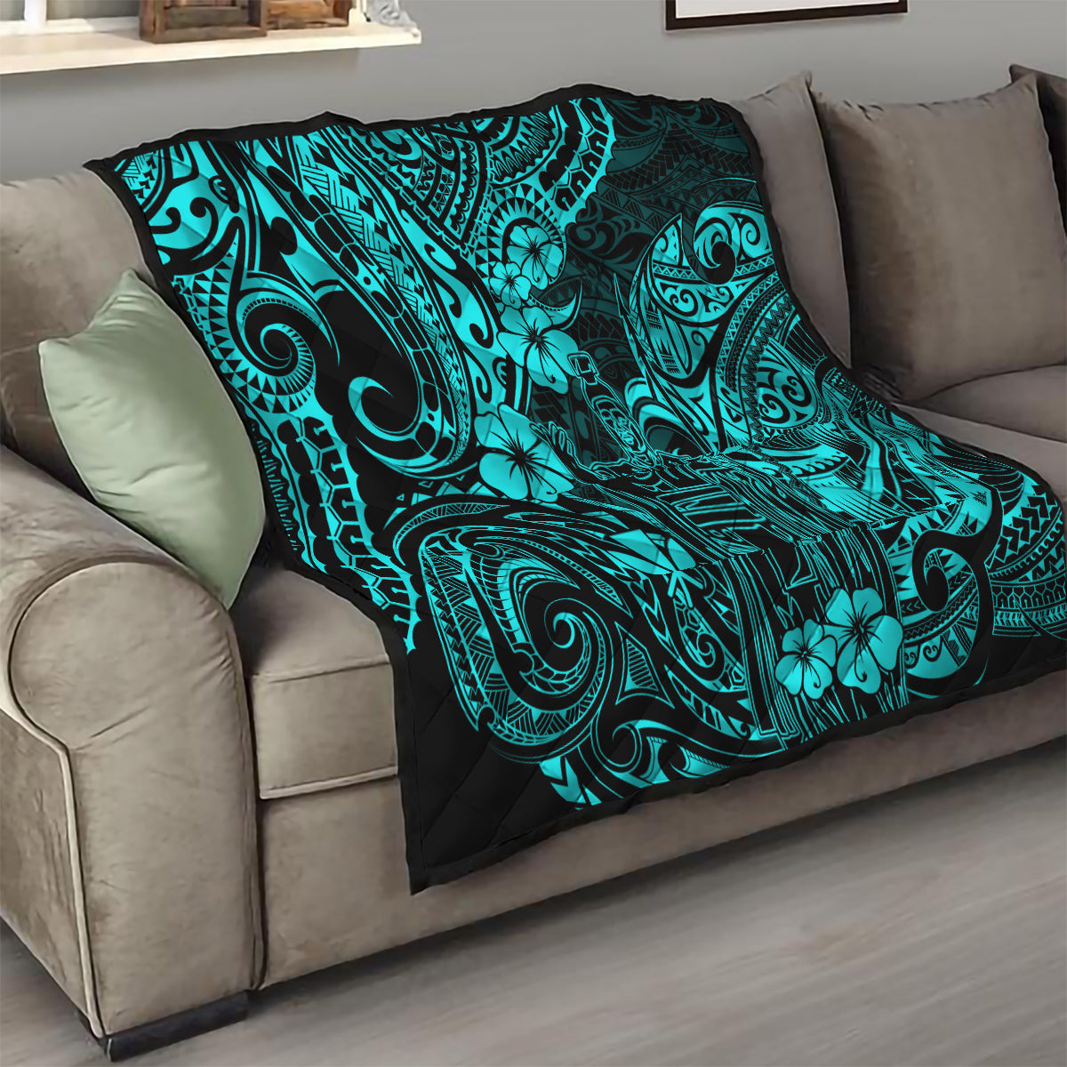 Turquoise Polynesian pattern quilt folded on beige sofa with black backing