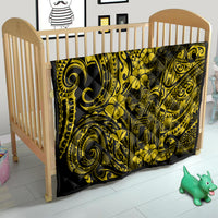 Yellow-and-black Polynesian pattern quilt on a wooden baby crib mattress