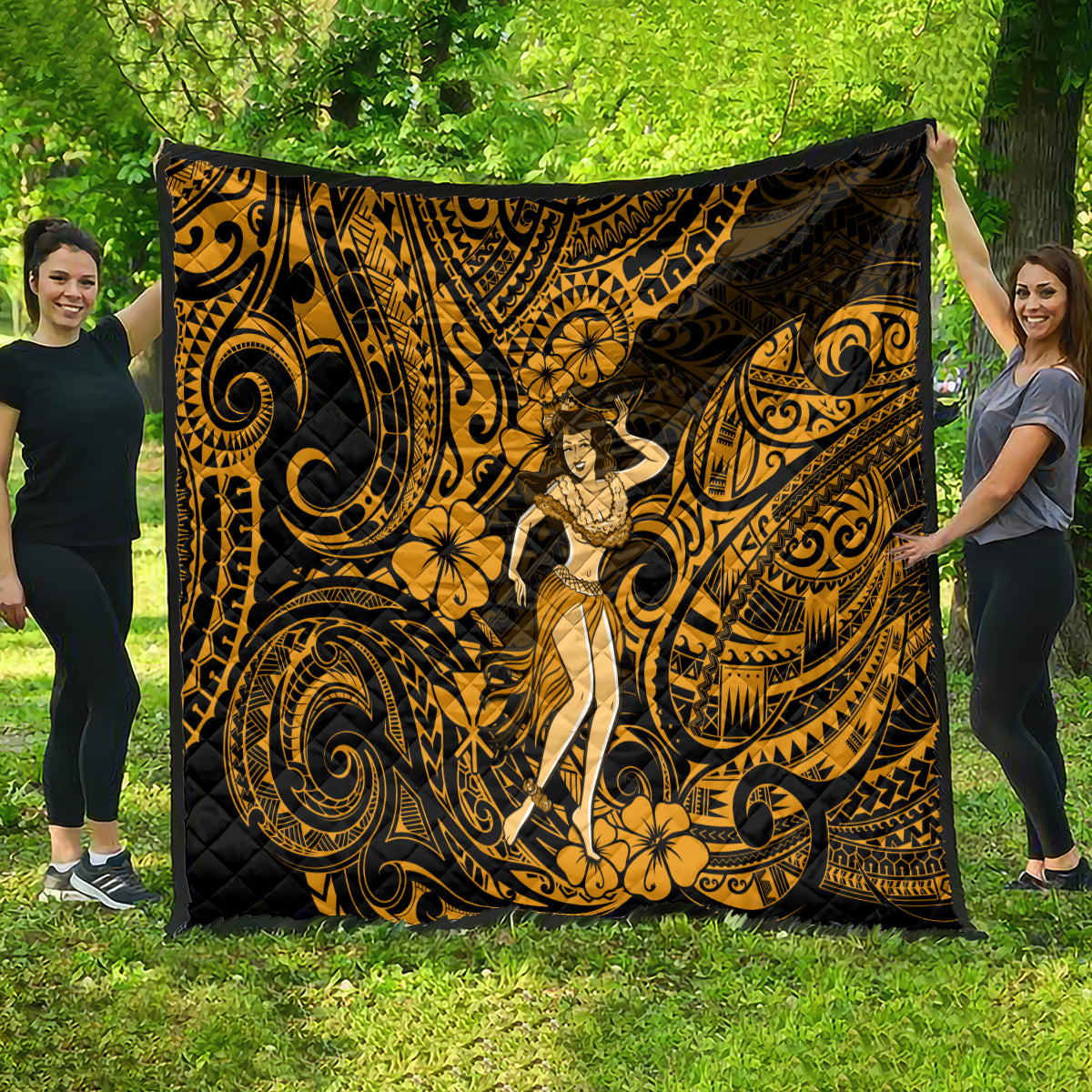 Gold and black Polynesian hula girl quilt spread wide outdoors with ornate swirl and flower motifs