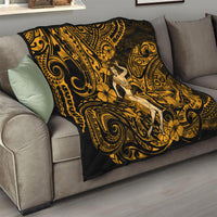 Gold and black Polynesian hula girl quilt folded on a living room sofa with bold scrollwork