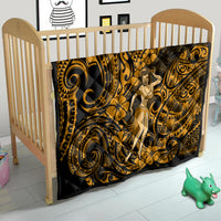 Gold and black Polynesian hula girl quilt placed in a wooden baby crib with swirl motifs