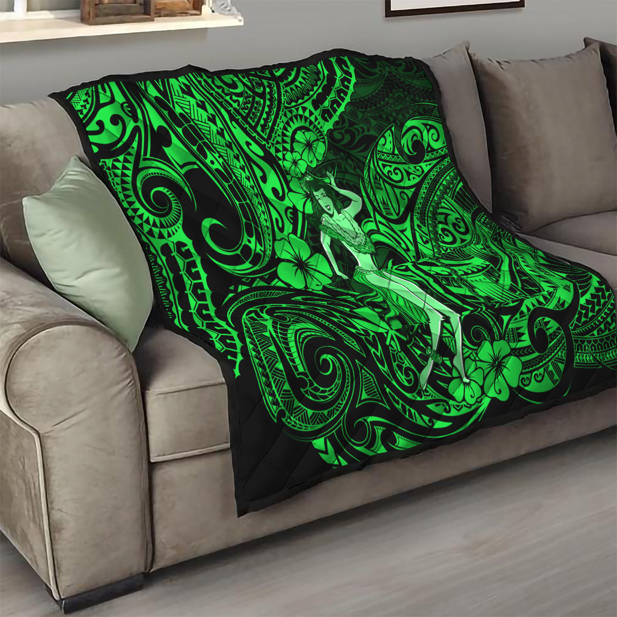Green and black Polynesian hula girl quilt folded on a sofa with swirling tribal print
