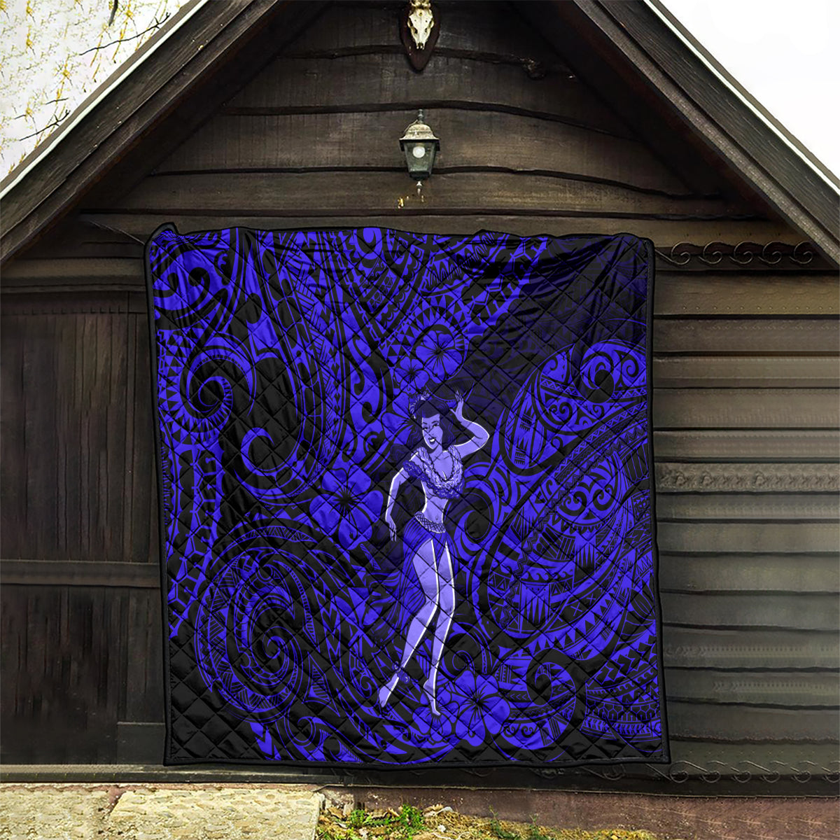 Hula girl quilt hanging on wooden wall, navy blue with spiral tribal designs