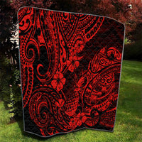 Red and black Polynesian pineapple quilt blanket draped on grass with curved swirl patterns