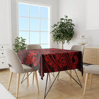 Red and black Polynesian tablecloth with pineapple and tiki designs on dining table.