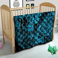 Blue Polynesian quilt blanket on baby bed, black border with swirl and flower print