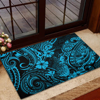 Blue rubber entry mat with pineapple and Polynesian swirl motifs under a doorway