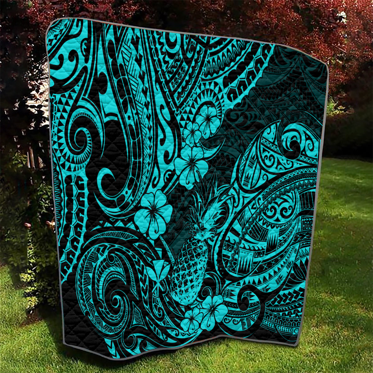 Turquoise Polynesian pattern quilt blanket with black backing and hibiscus-like flowers
