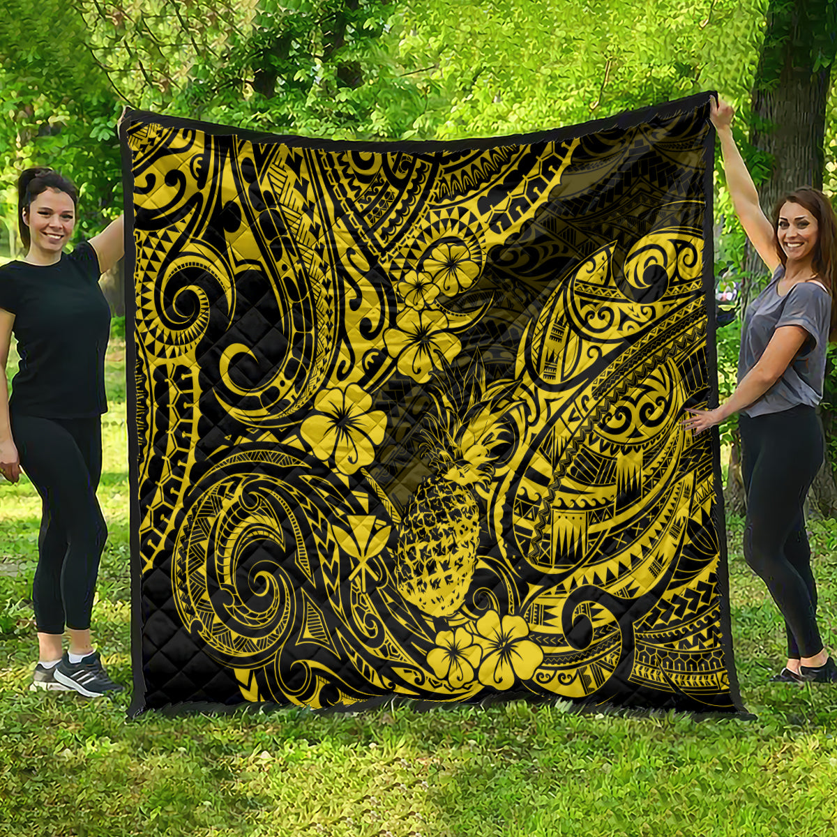 Yellow and black pineapple print quilt spread outdoors, visible ornate swirling motifs