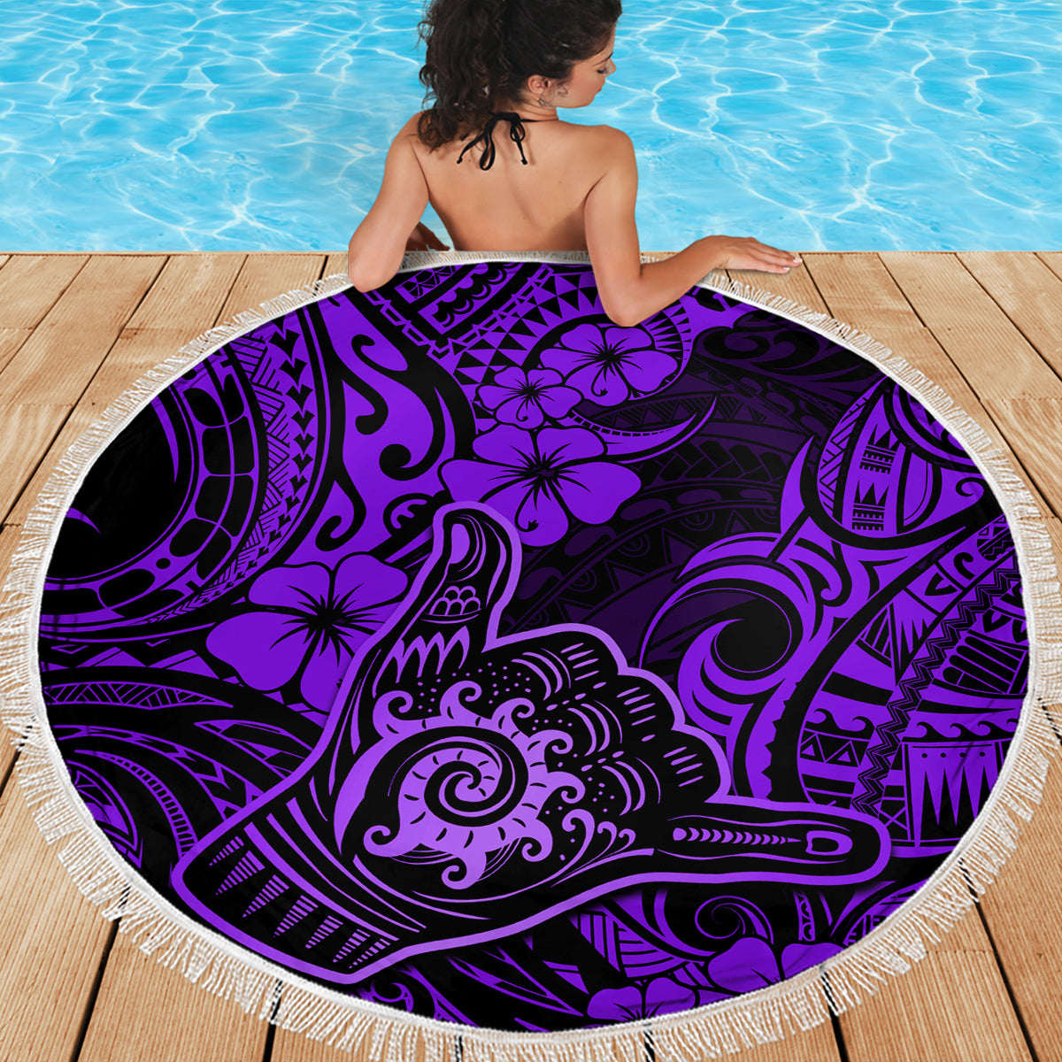 Round purple beach blanket with Polynesian-style print and white fringe edge on deck