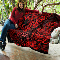 Red Polynesian pattern quilt draped on a couch with black spiral and flower motifs