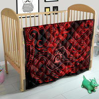 Red Polynesian pattern quilt on a crib with black swirls and floral motifs