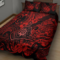Red and black patterned quilt with two square pillow shams on a bed