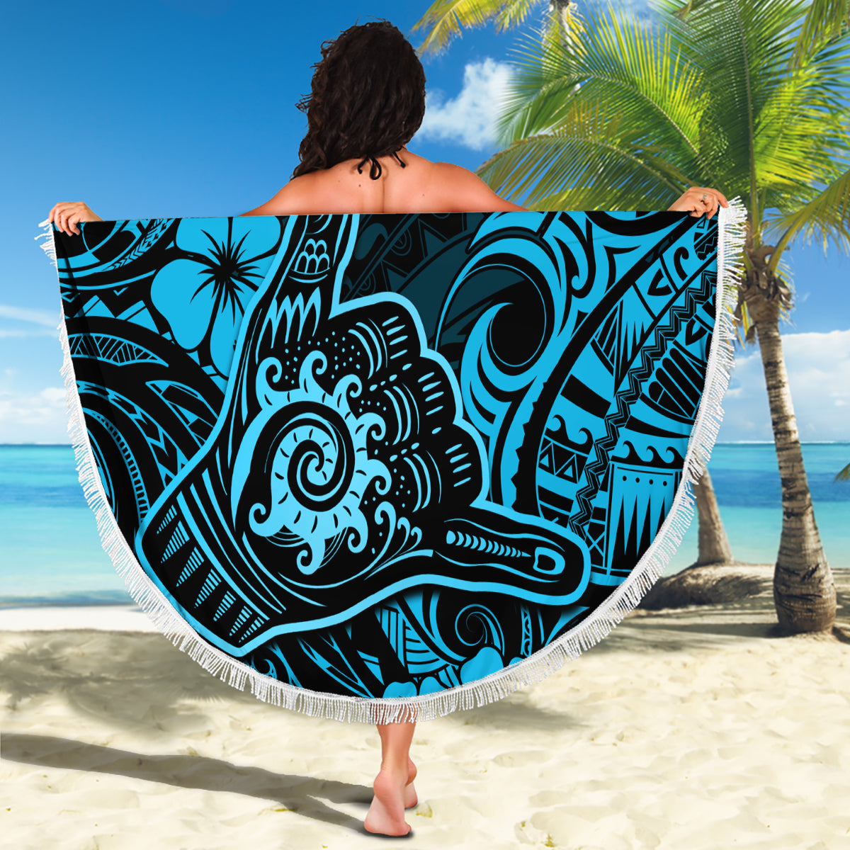 Round beach blanket held flat with bold Polynesian wave and hibiscus print, white fringe
