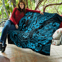 Blue Polynesian shaka pattern quilt with black backing, held over bench