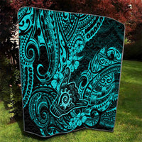 Turquoise Polynesian pattern quilt with black border laid on grass
