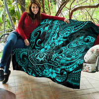 Turquoise Polynesian pattern quilt draped across seating area with black corner