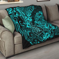 Turquoise and black Polynesian pattern quilt on a gray couch