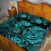 Turquoise and black patterned quilt and pillow shams on wooden bed frame