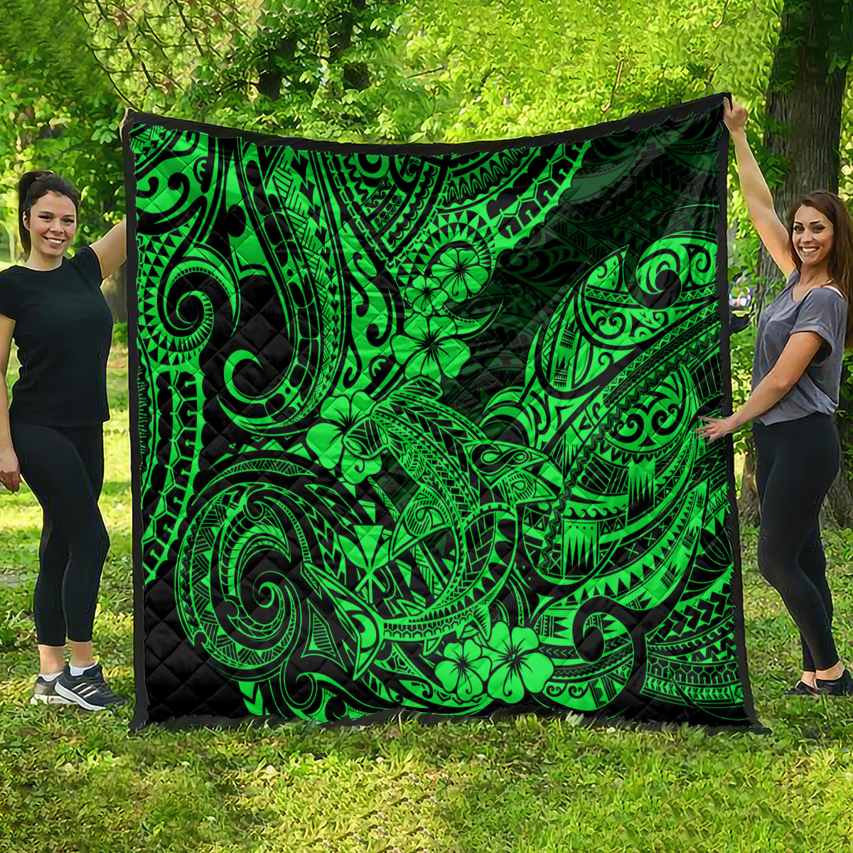 Green Polynesian pattern quilt spread outdoors, black backing with large floral and wave motifs
