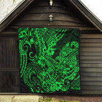 Green Polynesian pattern quilt hanging on a wooden wall, black backing with swirling designs