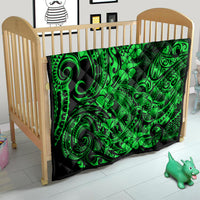 Green Polynesian pattern quilt on a small crib, black border with swirl and floral pattern