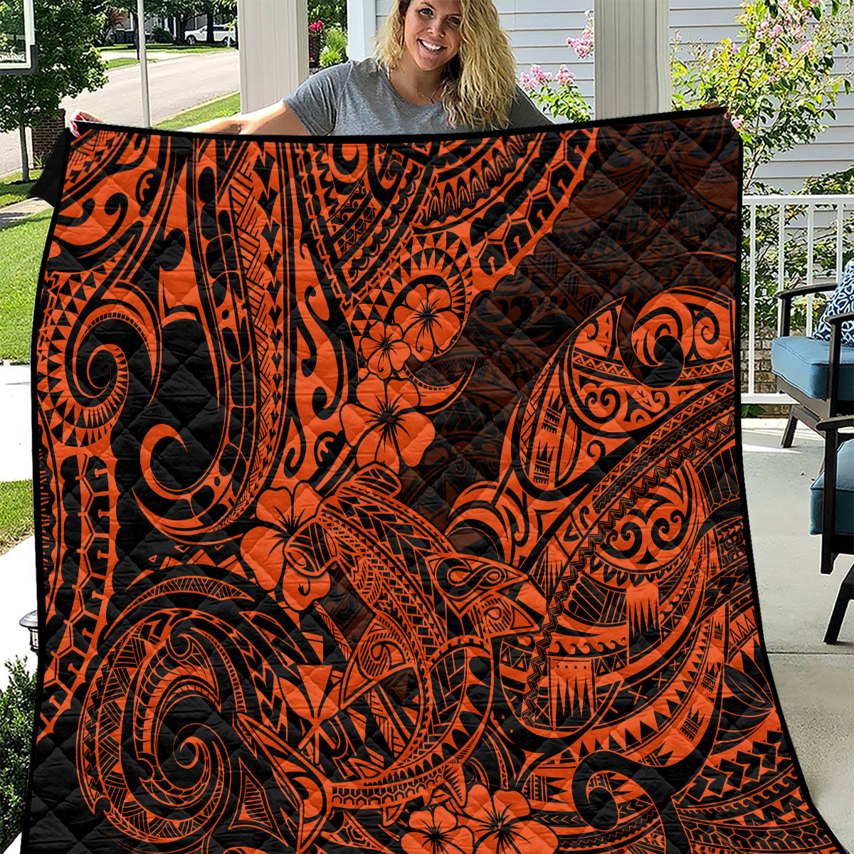 Orange and black Polynesian-style quilt with swirling tribal artwork and floral motifs