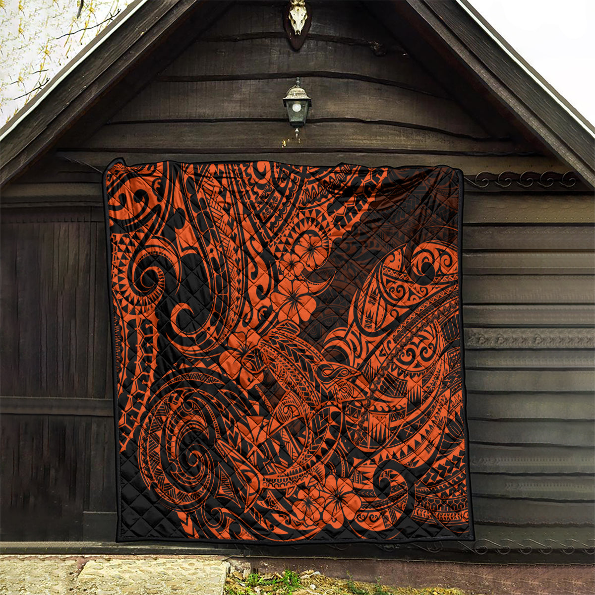 Orange and black Polynesian-style quilt hung in an entry, tribal swirl and flower pattern