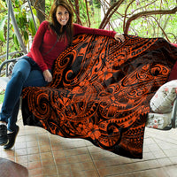 Orange and black Polynesian-style quilt draped on a bench, swirling tribal and flower design