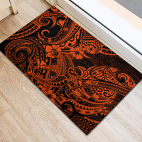Orange and black polynesian patterned rubber doormat laid flat on light wood floor.