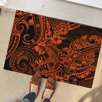 Orange and black polynesian patterned rubber doormat on outdoor concrete, foot visible.