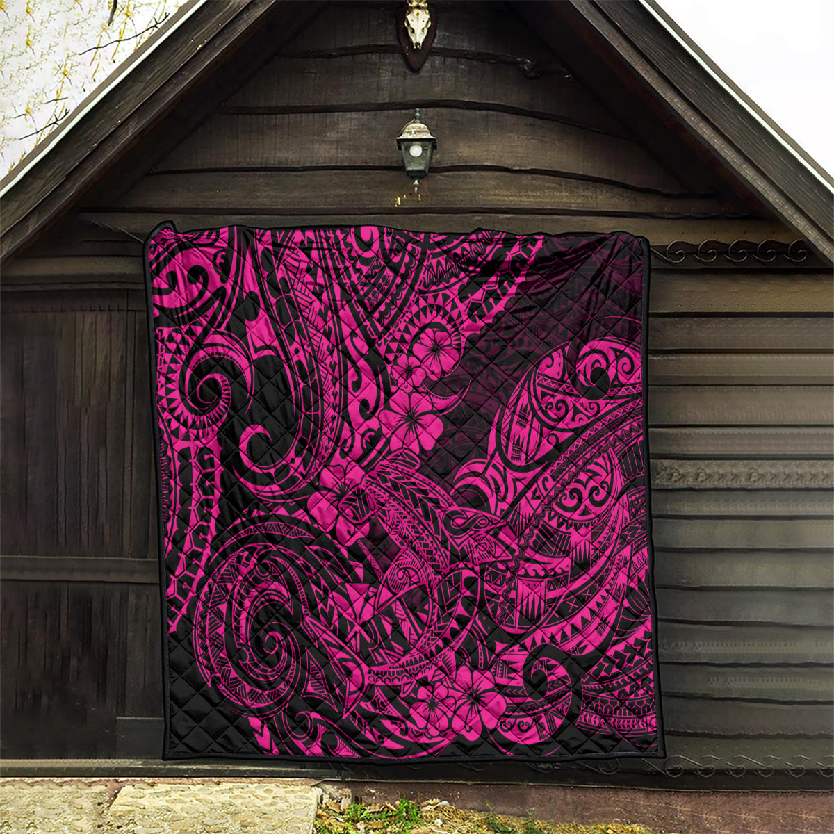 Pink and black Polynesian shark pattern quilt blanket hanging indoors