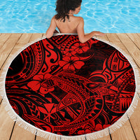 Round red beach blanket with black tribal hibiscus design and white fringe, on wooden deck