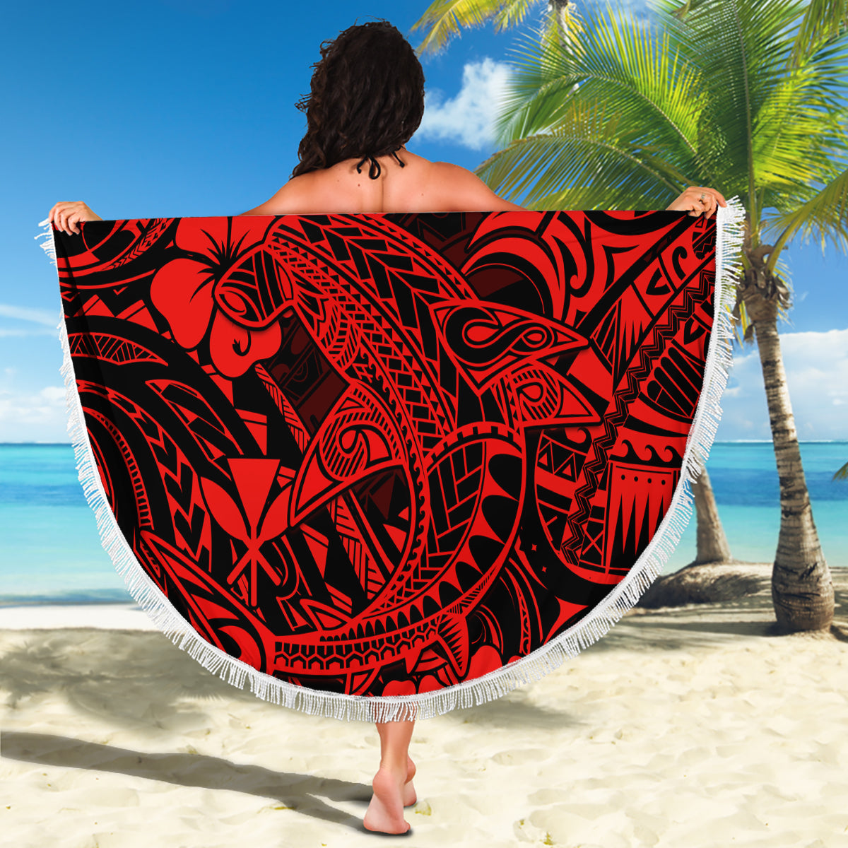 Red round beach blanket with black Polynesian-style tribal pattern and white fringe edge