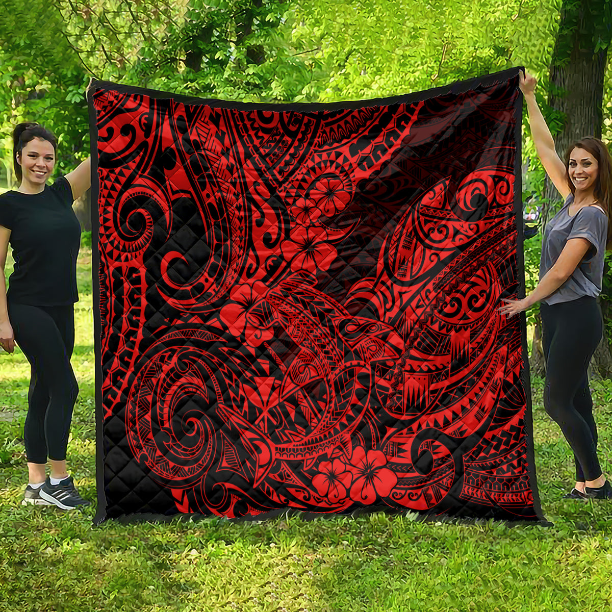 Red and black Polynesian shark pattern quilt, full square hanging outdoors.