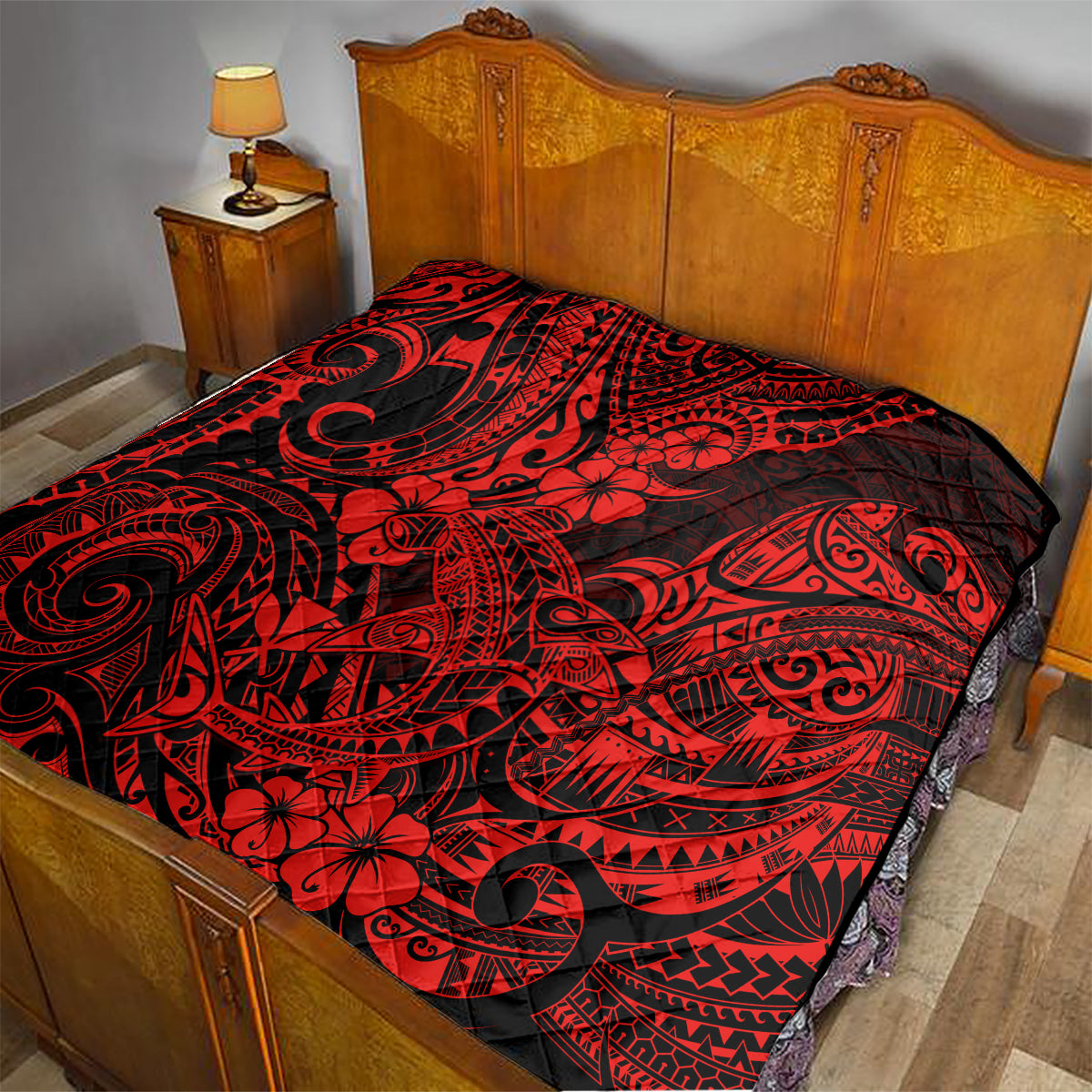 Red and black Polynesian shark pattern quilt on wooden bed, spread across top.