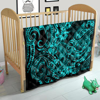 Turquoise shark motif quilt blanket on a baby bed/crib, black base with teal tribal pattern