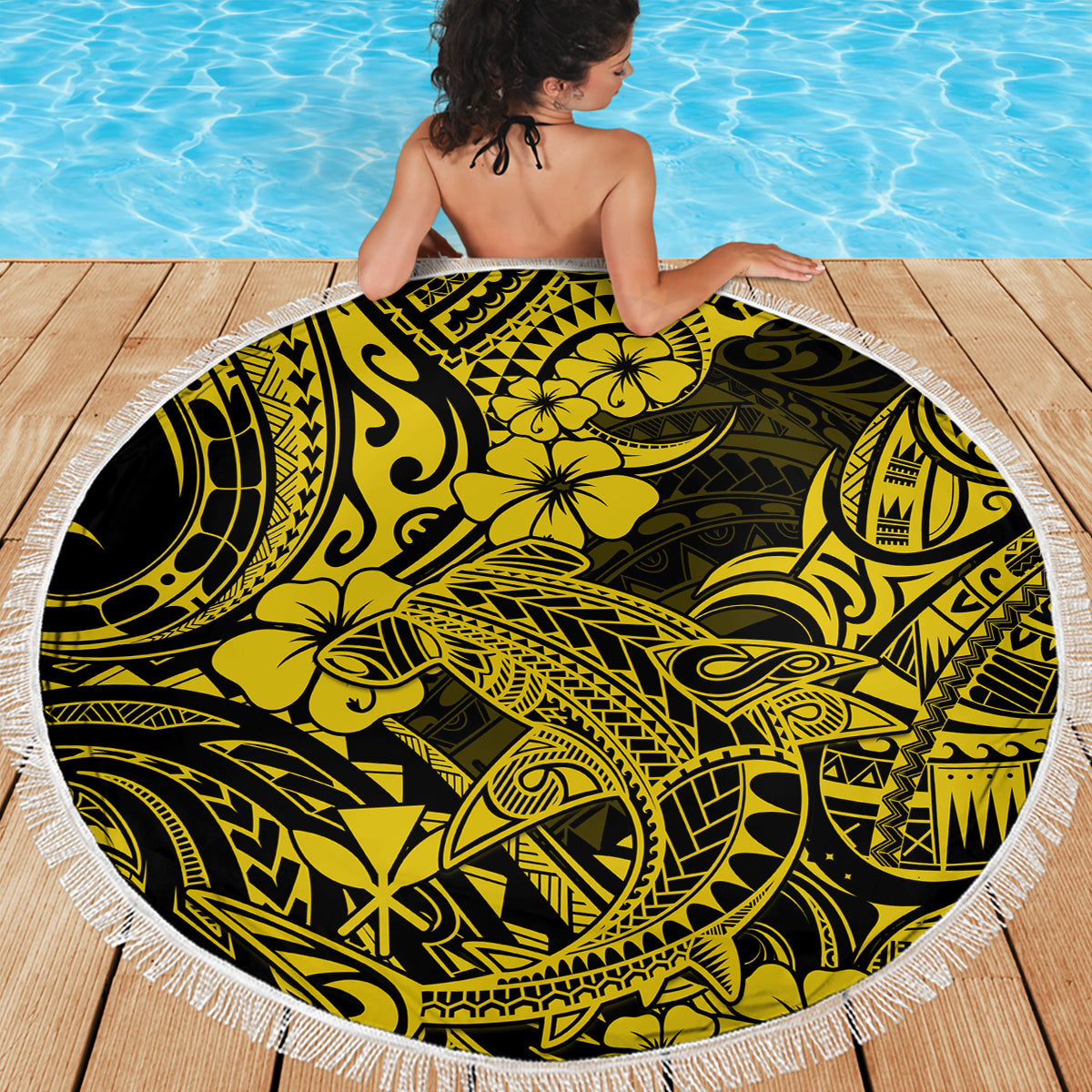 Round Polynesian print beach blanket in yellow and black with a white fringed border.