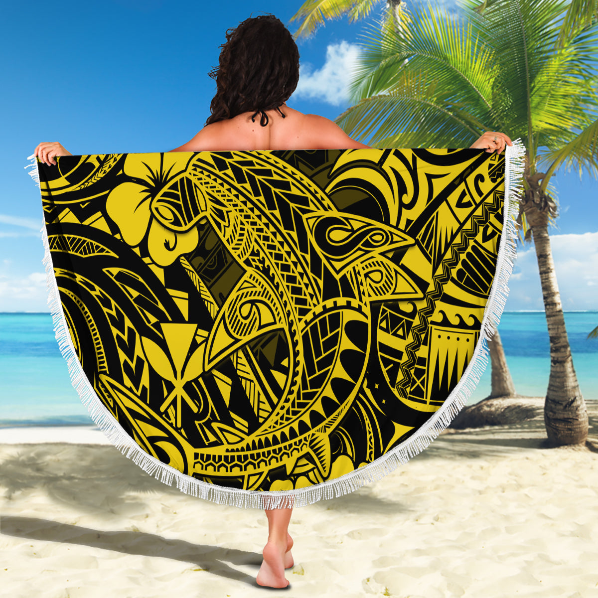 Round beach blanket with bold yellow-on-black tribal shark and hibiscus design plus fringe.