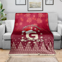 Red Christmas blanket draped on sofa with Santa riding reindeer, snowflakes and trees