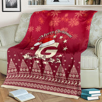 Red Christmas blanket on couch with Santa riding reindeer, stars, snowflakes, and patterns