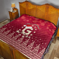 Red quilt blanket with “Merry Christmas” and Santa riding reindeer pattern on bed