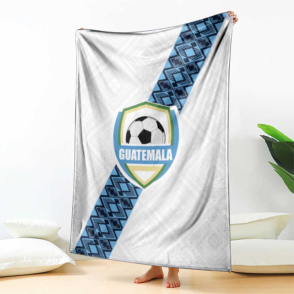 White Guatemala football blanket draped on floor with crest and blue geometric stripe