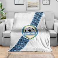 White Guatemala football blanket on couch with central crest and blue diagonal pattern