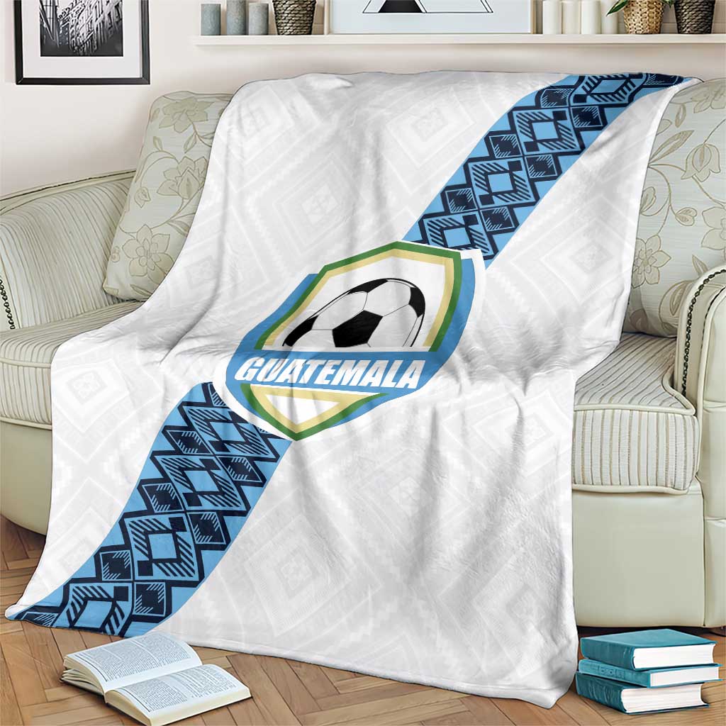 White Guatemala football blanket on sofa with blue diagonal stripe and crest
