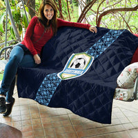 Navy football quilt held on couch, diamond quilting and Guatemala crest on diagonal stripe