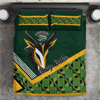 Green baby bedding set with rugby emblem, yellow trim, and plaid geometric pattern